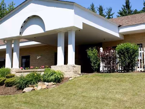 Exterior view of a single-story senior facility with white columns and landscaped entrance.