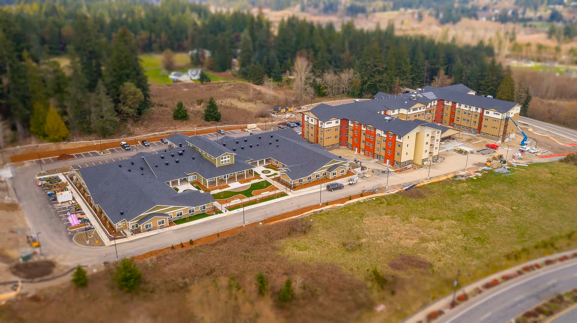 Aerial view of Fieldstone Memory Care Silverdale facility showing two large connected buildings with parking lots, surrounded by trees and open land.