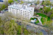 Aerial view of a beige, multi-story nursing home surrounded by trees and greenery.