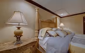 Well-appointed bedroom with a four-poster bed, decorative pillows, and matching bedside tables with lamps.