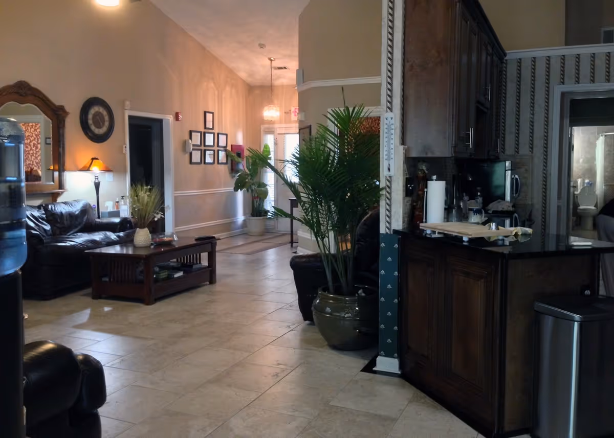 Lobby-style common area with leather seating, a coffee table, plants, and a kitchen counter.