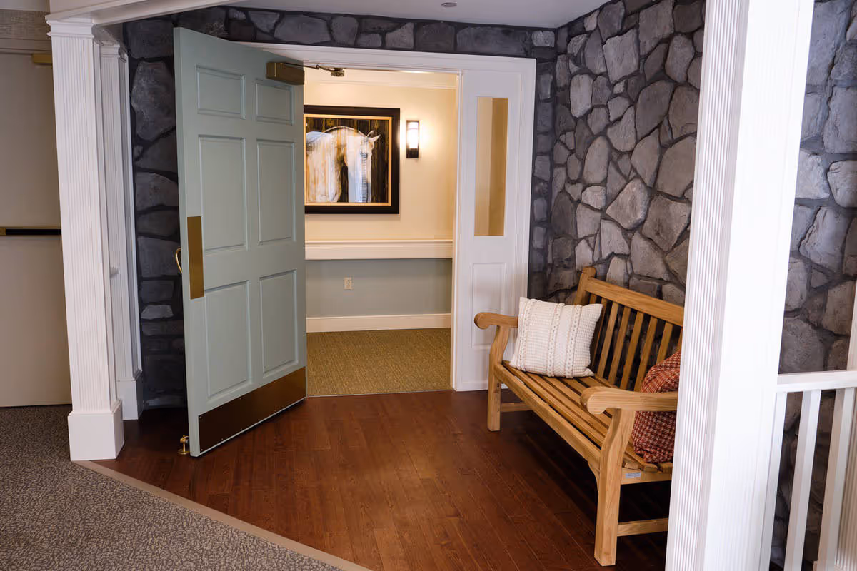 Open pale green door leading into an interior seating alcove with a wooden bench and pillows against a stone-pattern wall.