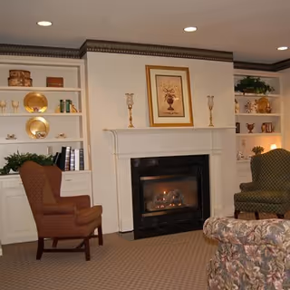 Cozy sitting room with a fireplace flanked by built-in shelves, upholstered chairs, and a floral sofa.