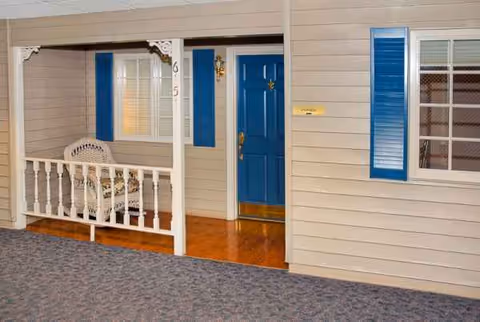 Front entrance of Life Care Center with blue door, beige siding, and white porch railing.