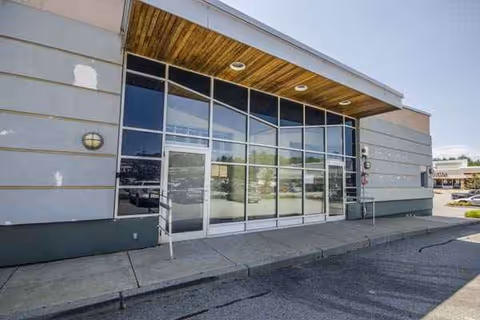 Exterior view of CareOne at New Bedford entrance with glass doors and wooden awning.