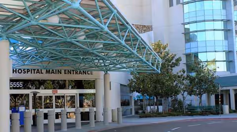 Hospital main entrance with turquoise metal canopy and glass doors at front exterior.