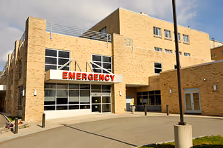 Brick hospital exterior with emergency entrance and large glass windows.