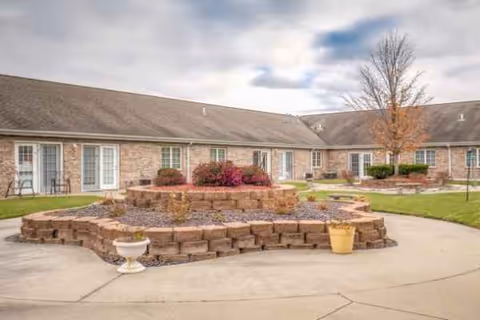Brick senior living facility exterior with circular stone planters in front.