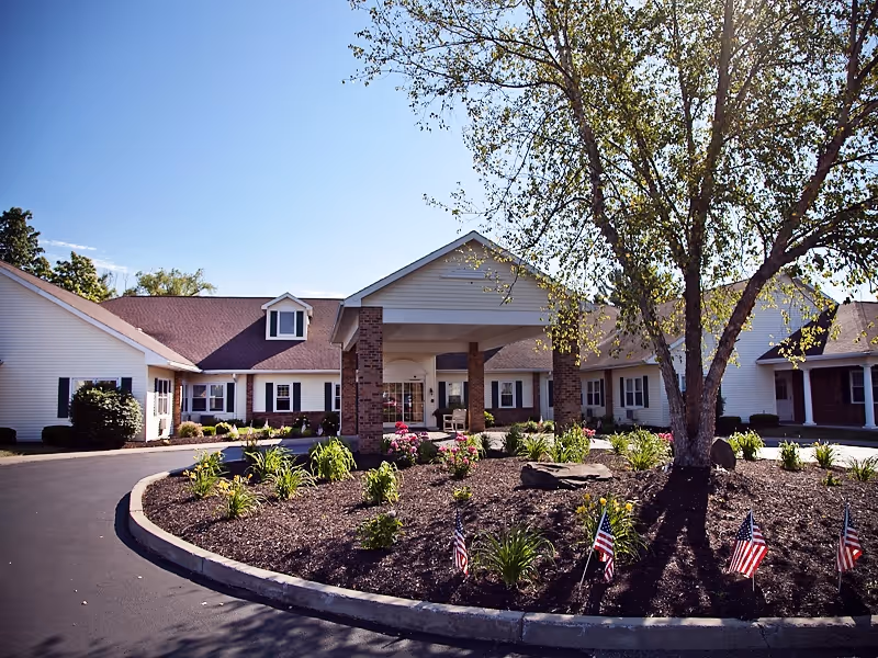 Exterior view of Keepsake Village at Greenpoint with entrance, curved driveway, and landscaped front yard.