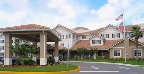 Exterior view of Sterling Court Sky Active Living facility with entrance and flagpoles.