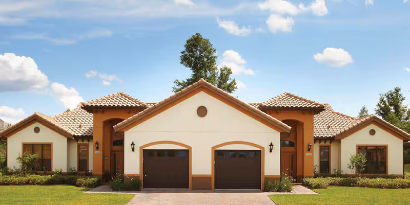Front exterior of a beige senior living building with three archways and two garages.