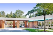 Exterior view of a senior living facility with brick columns and a covered entrance.