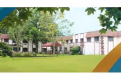 Low two-story rehabilitation and nursing center building with a grassy lawn, trees, and a covered courtyard.