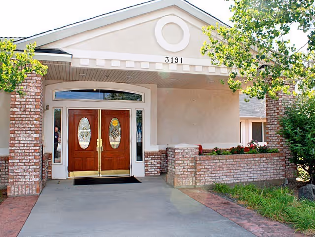 Covered entrance with double wooden doors, brick columns, planter walls, and address number 3191.
