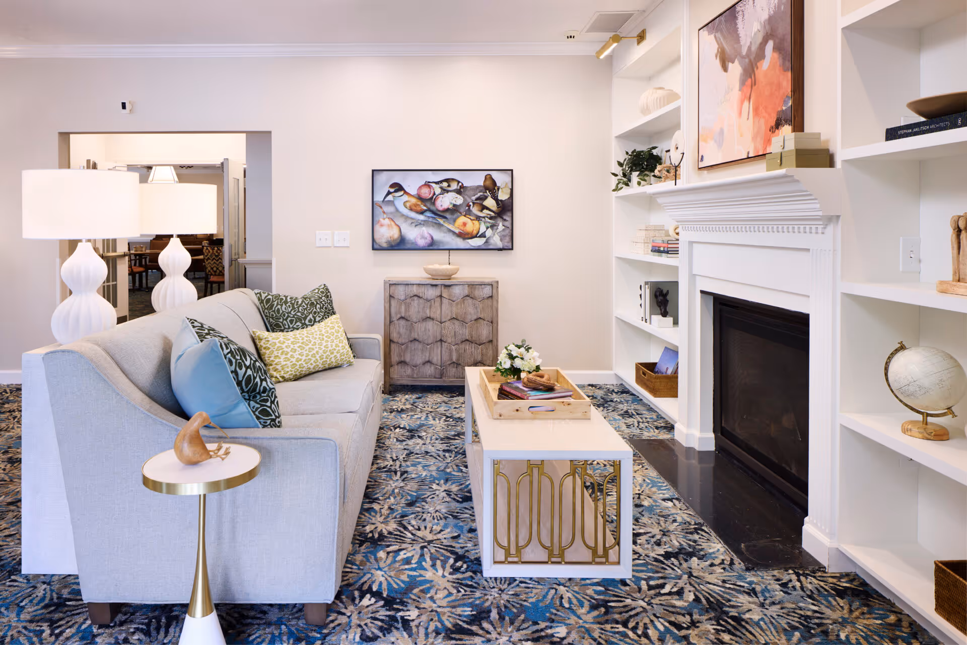 Bright, tastefully decorated living room with a sofa, coffee table, built-in shelving and a fireplace.