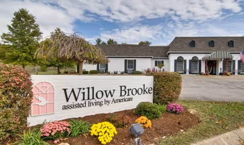 Exterior view of Willow Brooke assisted living building with a landscaped sign in foreground.