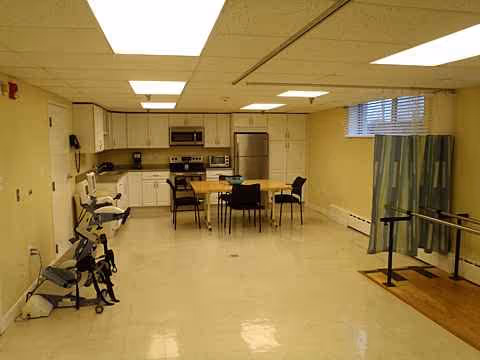 Interior common room with kitchenette, dining table, chairs, and mobility equipment.