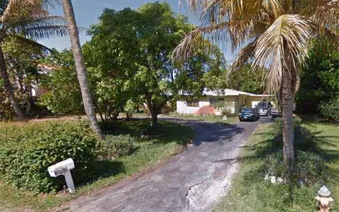 Exterior view of Capricorn Retirement Home Inc showing a driveway, trees, and a parked car.
