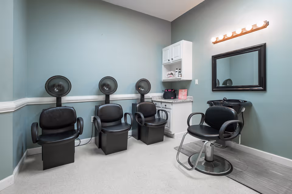 Salon area with hair dryers, mirrors, and cabinetry inside a senior living facility.