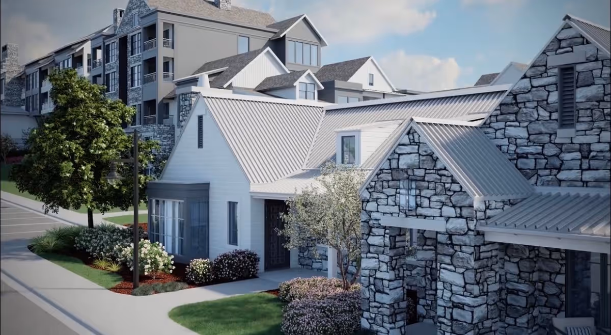 Exterior view of a senior living facility featuring multiple buildings with stone and white siding, metal roofs, landscaped greenery, and a parking area.