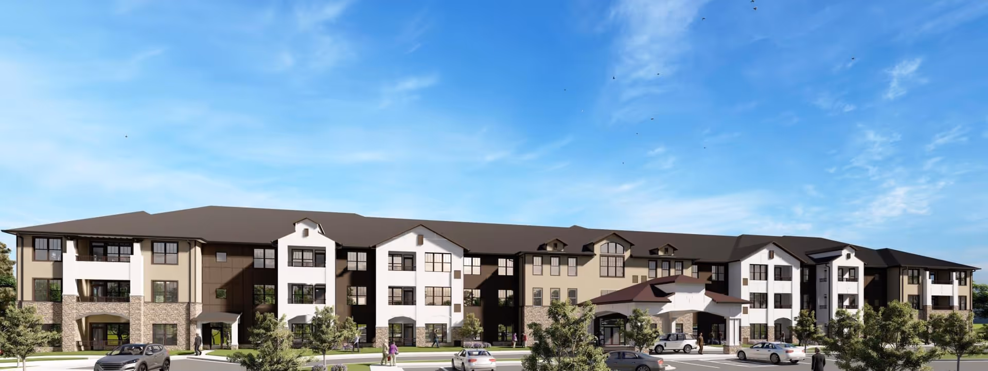 Front exterior of a three-story senior living facility with landscaped grounds, parked cars, and a clear blue sky.