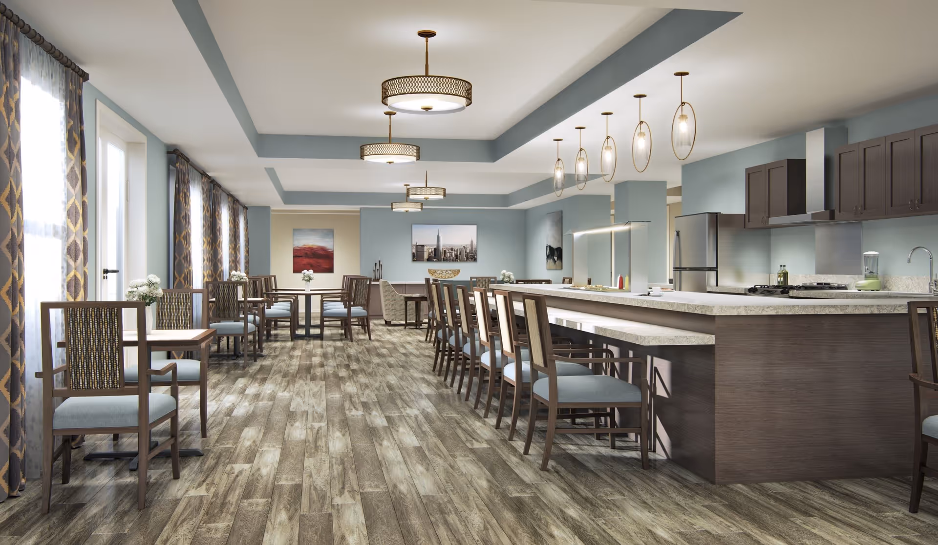 A spacious dining area with wooden flooring, multiple tables and chairs arranged along the left side, and a long kitchen island with bar stools on the right. The kitchen area features modern appliances, including a refrigerator, stove, and sink, with pendant lights hanging above the island. The walls are painted light blue with artwork and large windows with patterned curtains letting in natural light.