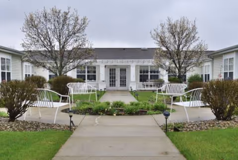Front exterior of Maplecrest Assisted Living with white benches and central courtyard.