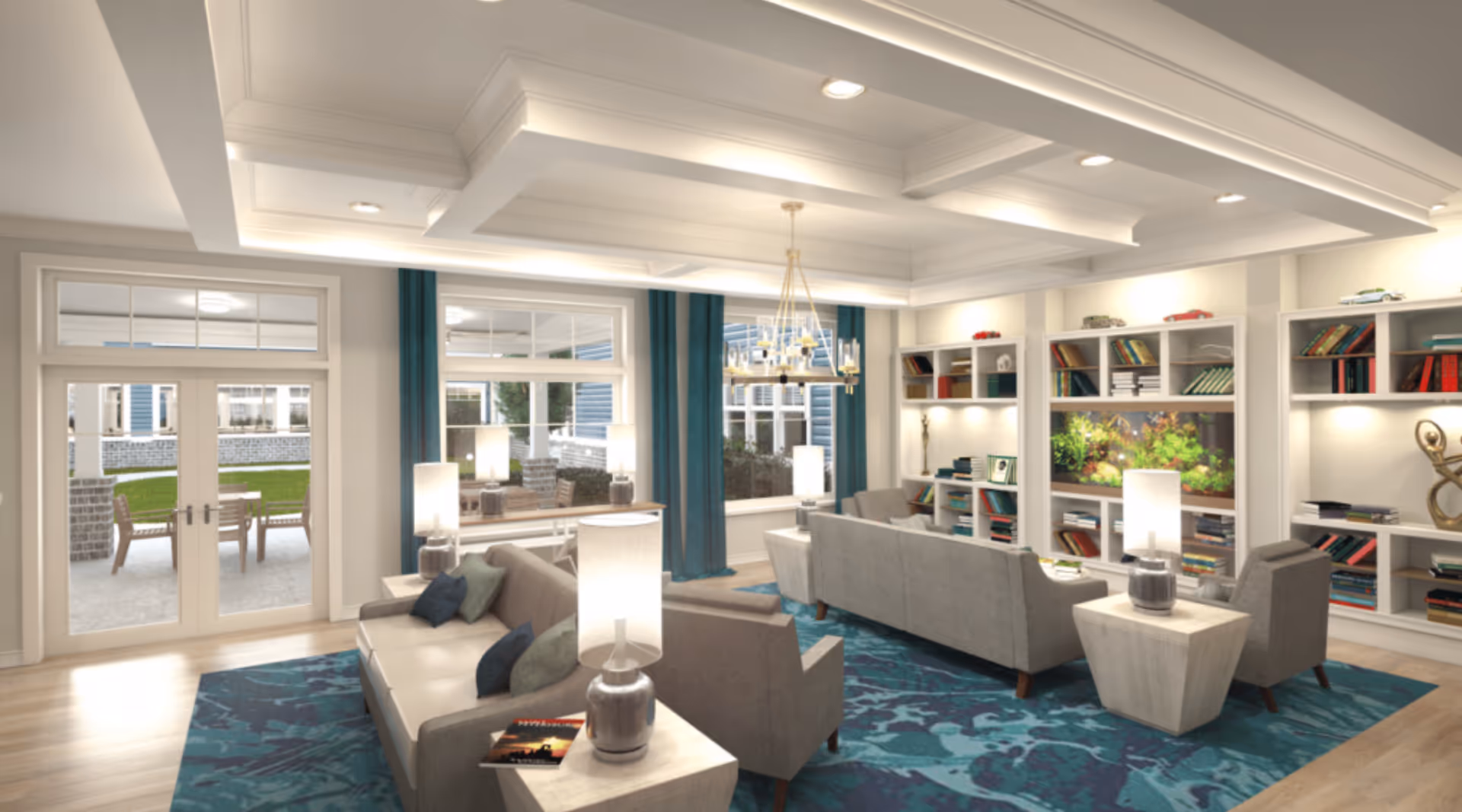 A spacious and well-lit living room with modern decor, featuring two gray sofas, armchairs, a blue patterned rug, multiple table lamps, built-in white bookshelves filled with books and decorative items, and a large fish tank. Large windows and glass doors open to an outdoor patio area with chairs and greenery.