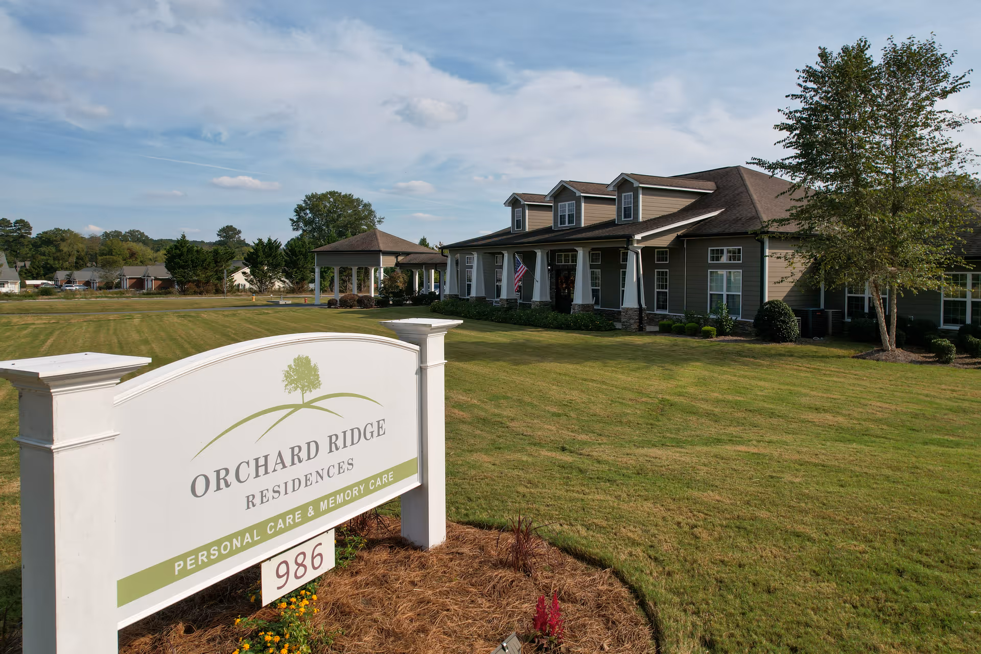 Orchard Ridge Residences sign on a grassy lawn with the facility building in the background.