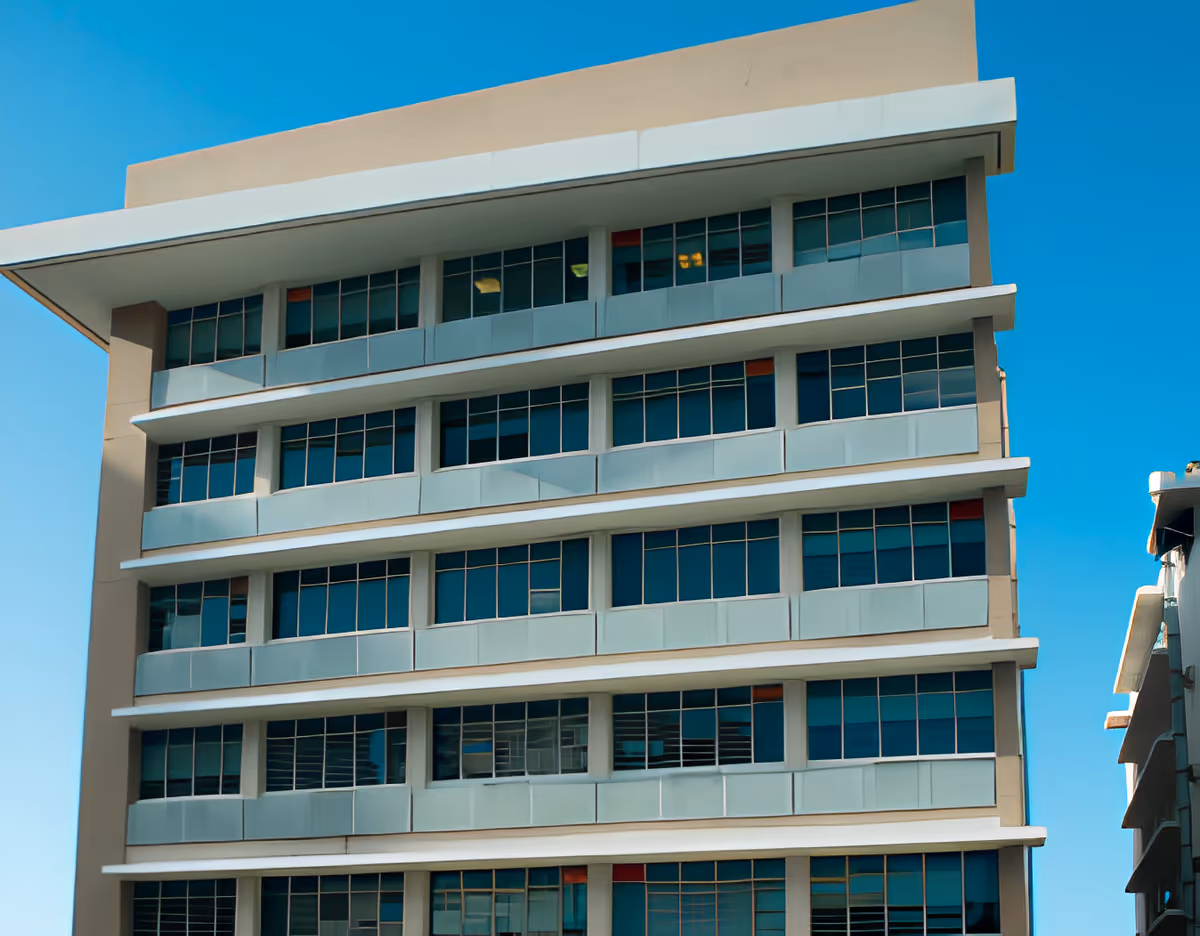 Exterior view of a multi-story modern building with large windows under a clear blue sky.