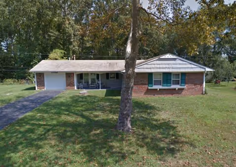 A single-story brick senior living facility with a driveway and front lawn.