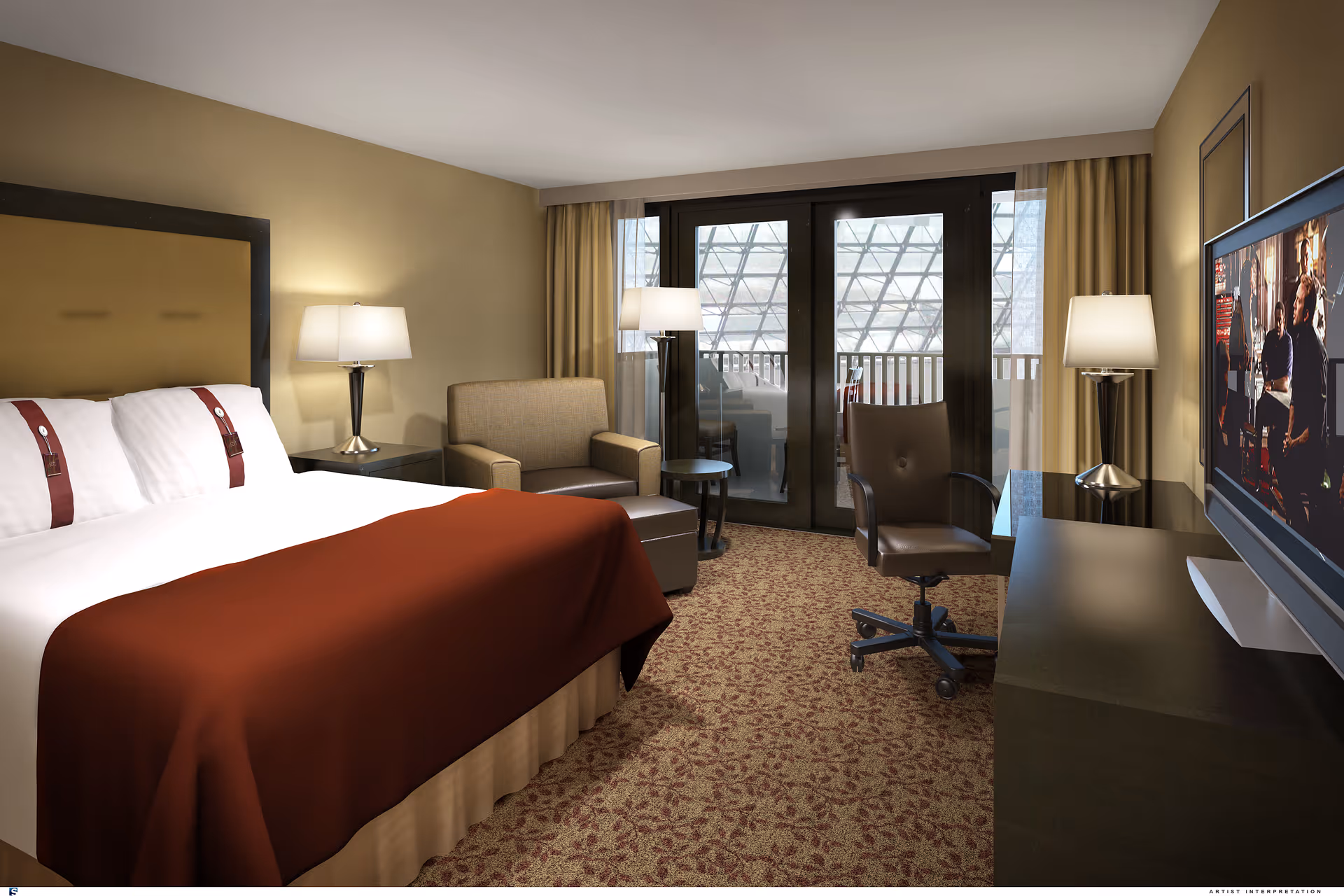 A well-lit bedroom with a large bed covered with white sheets and a brown blanket. There are two bedside tables with lamps, a comfortable armchair with an ottoman, a small round table, and an office chair in front of a desk with a flat-screen TV mounted on the wall. Large glass doors with curtains lead to a balcony outside.