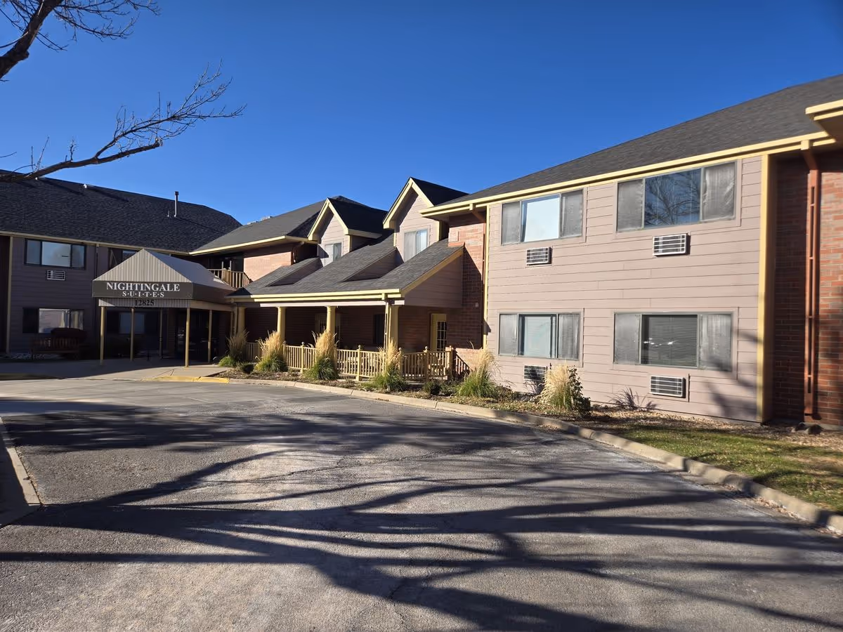 Front exterior of a two-story senior living building with a covered entrance canopy reading "Nightingale Suites" and a parking area in front.