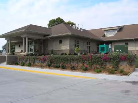 Exterior of Eastern Star Masonic Home senior living facility with a covered entrance and landscaped shrubs.