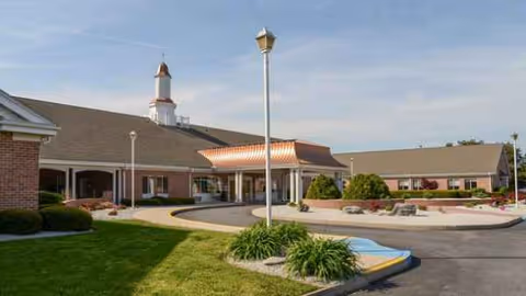 Exterior view of Carlisle Skilled Nursing and Rehabilitation Center with entrance, drive, and landscaping.