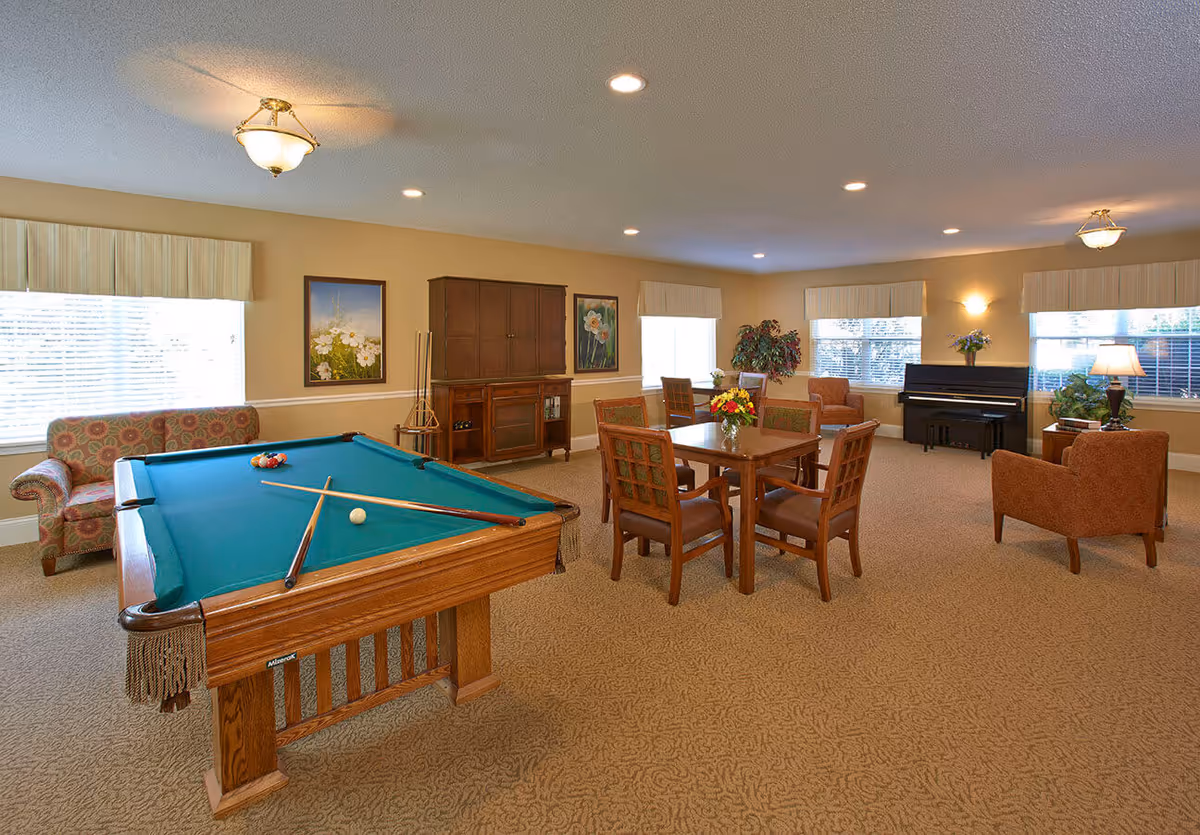 Spacious common room with a pool table, seating areas, a dining table, and a piano.