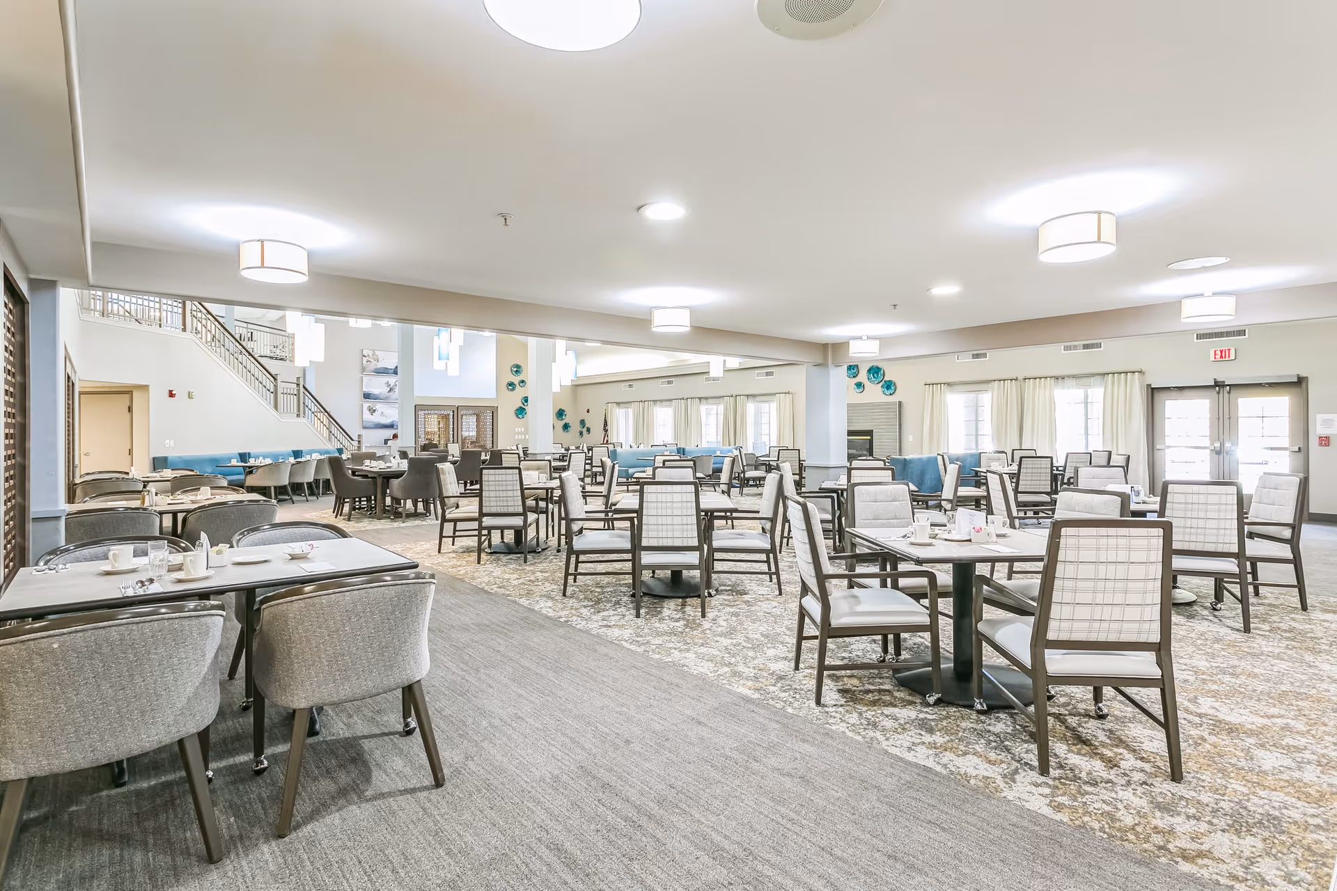 Spacious, well-lit dining room with multiple tables and chairs arranged for residents in a senior living facility.