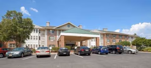 Exterior view of Brookdale Monroe senior living facility with parked cars and a covered entrance.