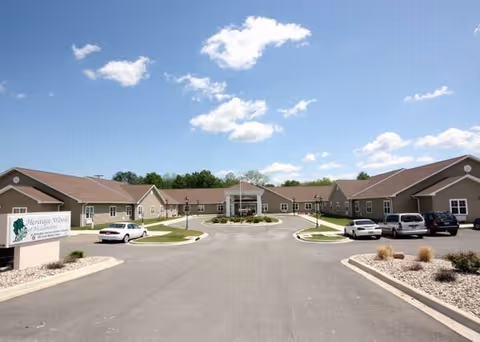 Wide exterior view of Fox Meadows Supportive Living with circular driveway and parked cars.