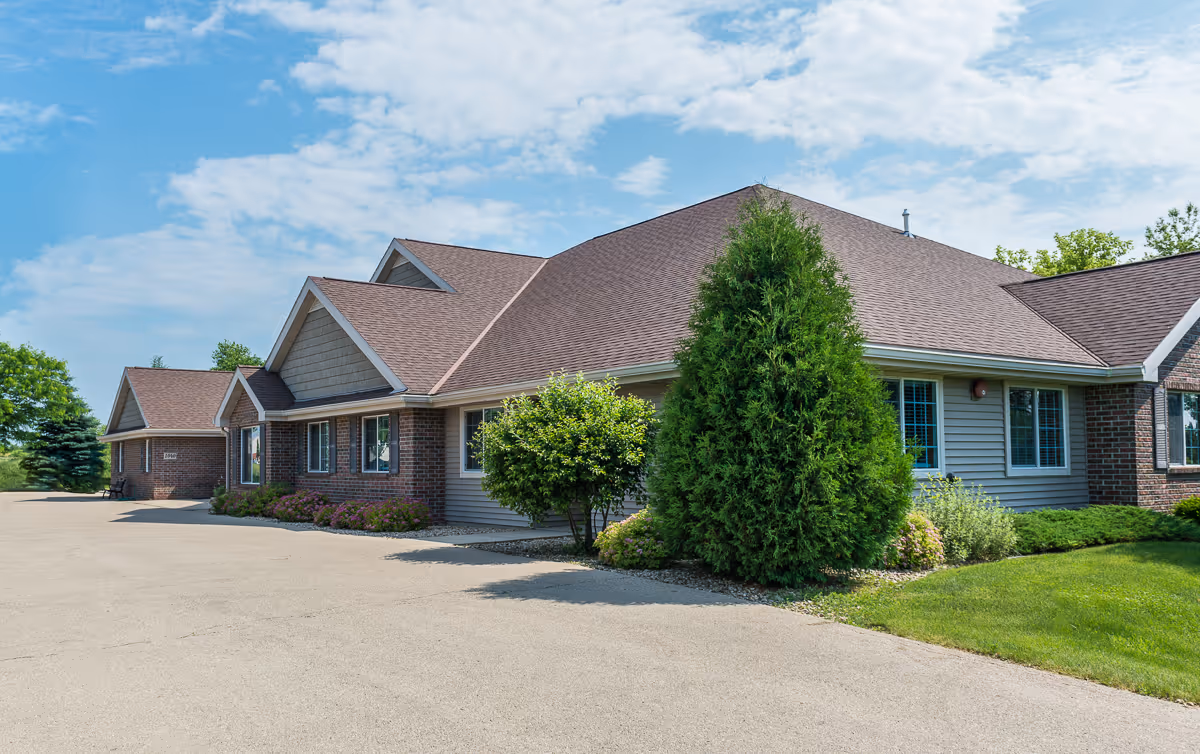 Exterior view of a brick and siding senior living building with landscaped grounds.