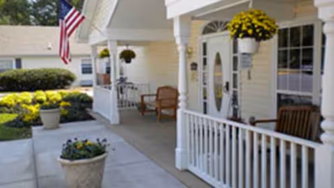 Front porch of Autumn Lake Healthcare at Silver Spring with chairs and potted plants.