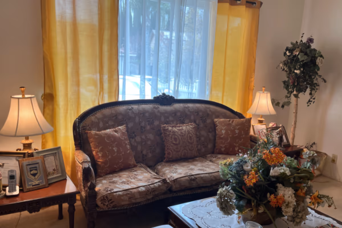 Elegant living room with ornate sofa, coffee table centerpiece, and warm yellow curtains.