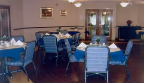 Senior living facility dining room with blue tablecloths and neatly arranged tables.