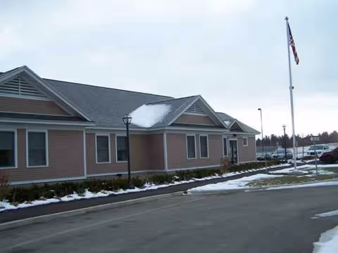 Exterior view of Rising Hill senior living facility with flagpole and snow.