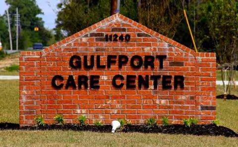 A brick sign reading Gulfport Care Center stands on a manicured lawn.