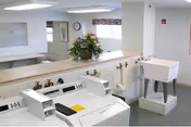 Laundry room with washers and dryers, a folding counter topped by a floral arrangement, and a utility sink.