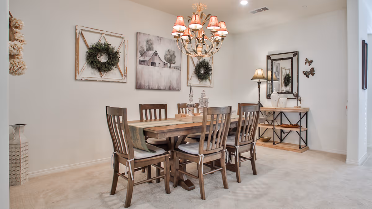 Bright, neutrally decorated dining room with a wooden table and six chairs, a chandelier, wall art, and a side console table with a lamp and mirror.
