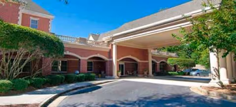 Exterior view of Dunwoody Place entrance with brick arches and a covered driveway.