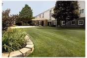 Front exterior of a two-story building with a manicured lawn, landscaping, and a covered entrance.