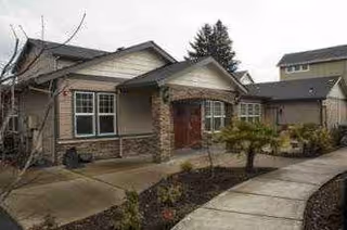 Single-story senior living facility exterior with curved walkway and landscaped front.